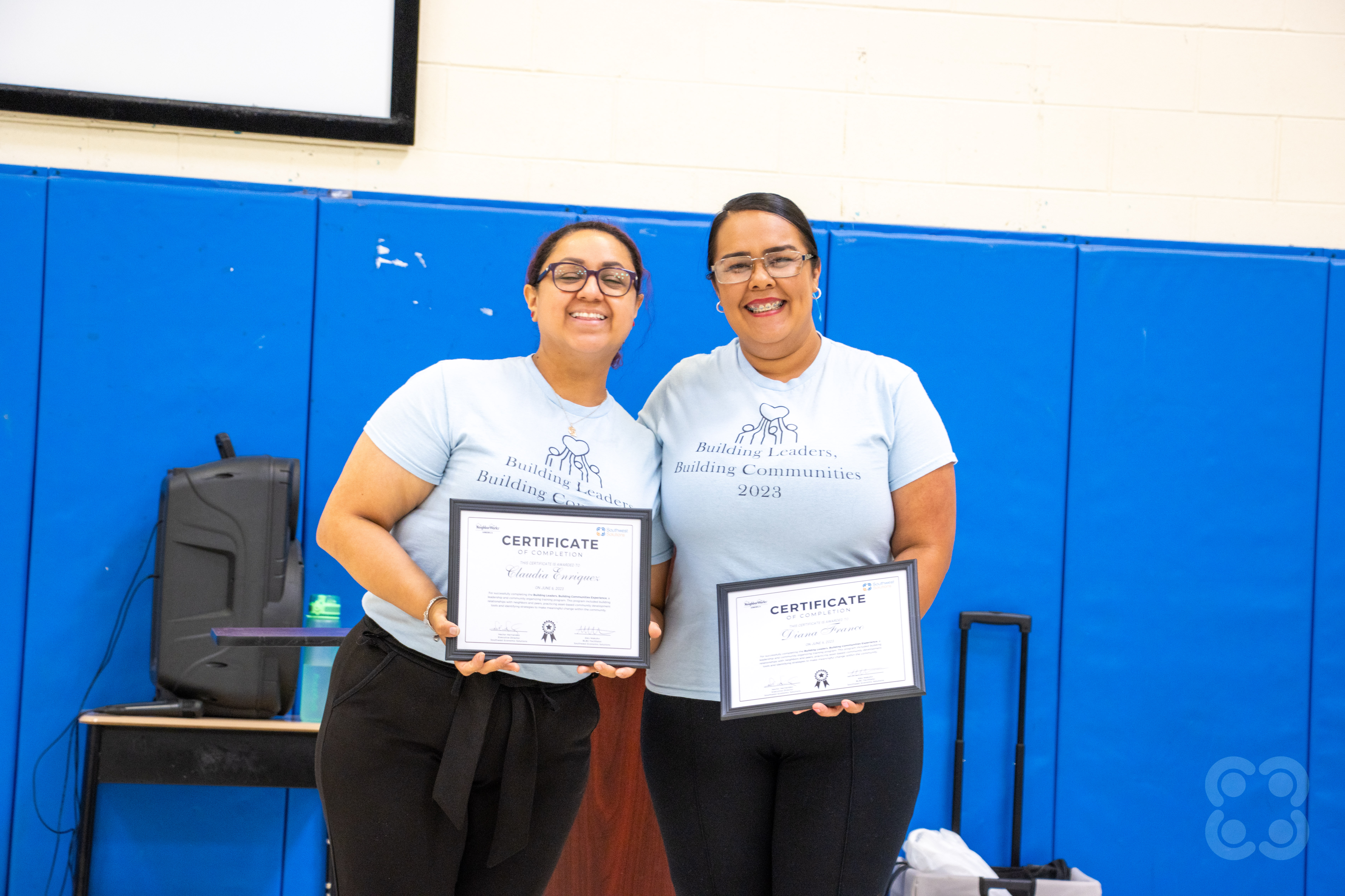 Claudia and Diana holding their certification of completion of the Building Leaders, Building Communities program